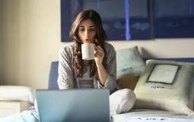 Woman drinking tea in front of laptop